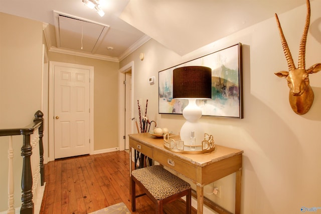 hall with attic access, crown molding, baseboards, and hardwood / wood-style flooring
