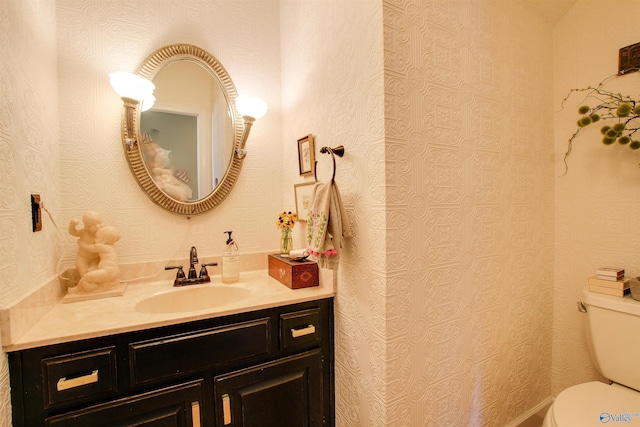 bathroom featuring wallpapered walls, toilet, and vanity