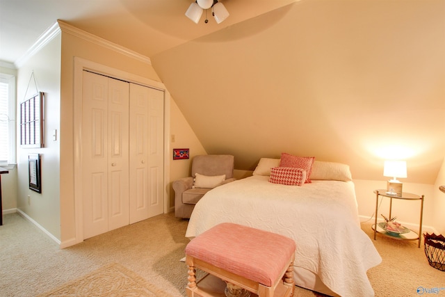 carpeted bedroom with a closet, lofted ceiling, baseboards, and ornamental molding