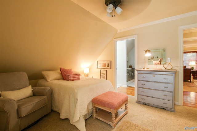 bedroom featuring light carpet, ornamental molding, a ceiling fan, ensuite bathroom, and vaulted ceiling