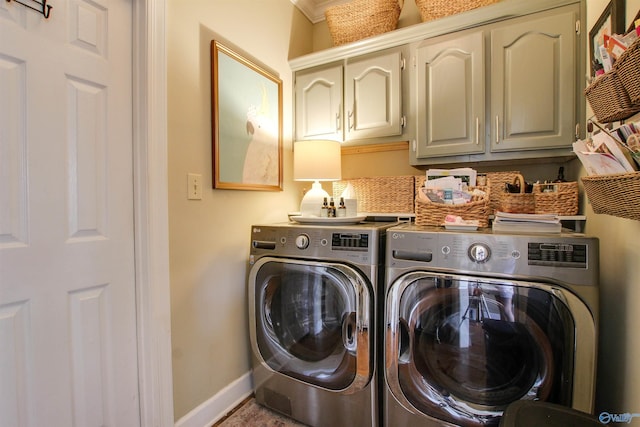 washroom with cabinet space, washer and dryer, and baseboards