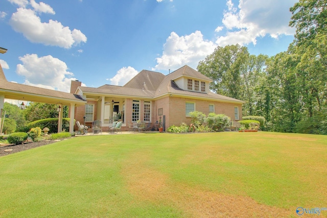 view of front of house with a front yard, a patio area, brick siding, and ceiling fan