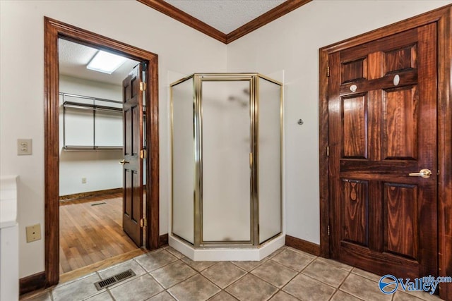 bathroom with ornamental molding, a textured ceiling, hardwood / wood-style flooring, and a shower with shower door