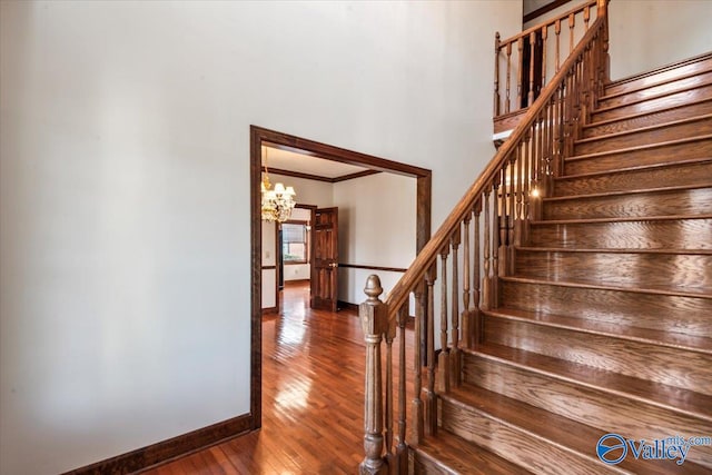 staircase with wood-type flooring and a chandelier