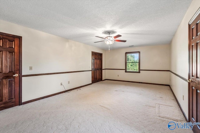 spare room featuring ceiling fan, light colored carpet, and a textured ceiling