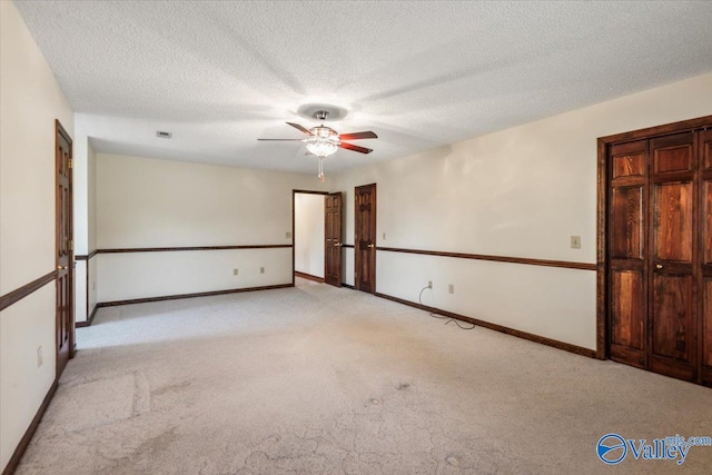 carpeted spare room with ceiling fan and a textured ceiling