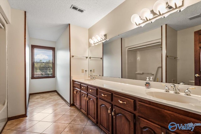 bathroom with tile patterned flooring, vanity, and a textured ceiling