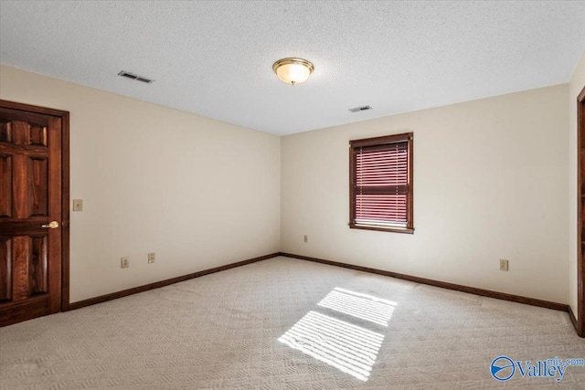 carpeted empty room featuring a textured ceiling