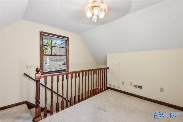 additional living space featuring a textured ceiling, light colored carpet, and lofted ceiling