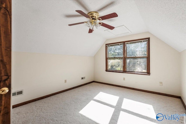 additional living space featuring light carpet, a textured ceiling, vaulted ceiling, and ceiling fan