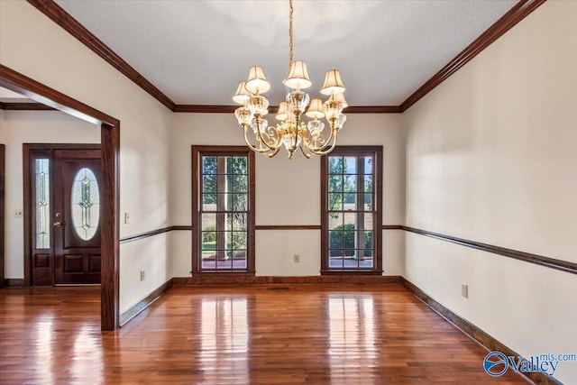 unfurnished dining area featuring crown molding, dark hardwood / wood-style flooring, and a notable chandelier