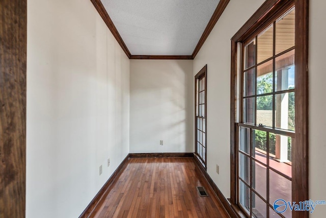 spare room with dark hardwood / wood-style floors, ornamental molding, and a textured ceiling