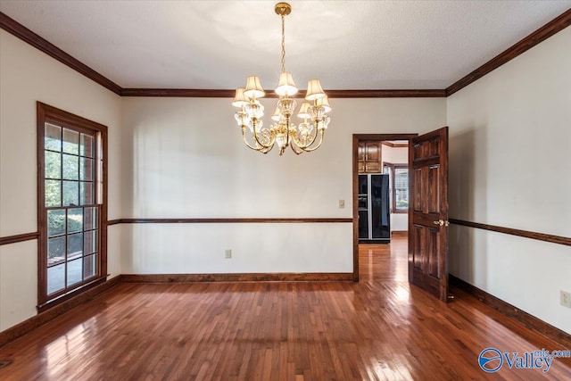 unfurnished dining area featuring a textured ceiling, dark hardwood / wood-style flooring, an inviting chandelier, and crown molding