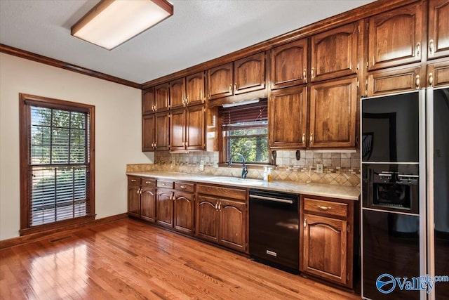 kitchen with a wealth of natural light, crown molding, black appliances, and light wood-type flooring