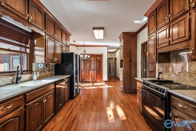 kitchen featuring backsplash, dark wood-type flooring, black appliances, crown molding, and sink