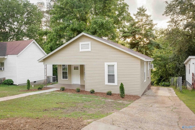 view of front facade featuring a front lawn, a porch, driveway, and view of scattered trees