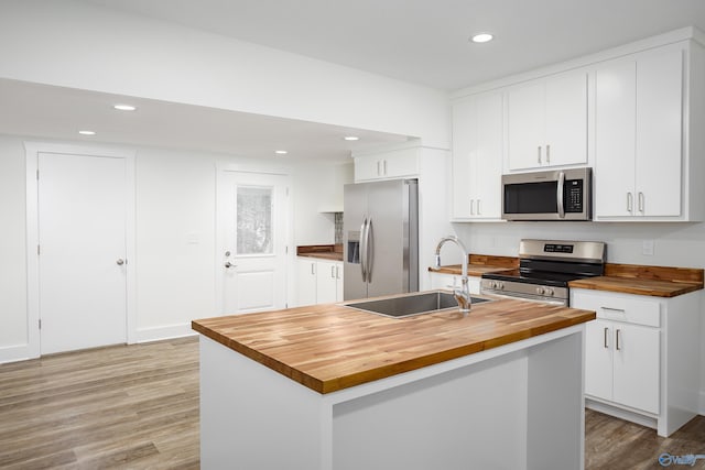 kitchen with wooden counters, appliances with stainless steel finishes, a sink, white cabinetry, and recessed lighting