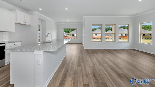 kitchen featuring sink, an island with sink, light hardwood / wood-style floors, white cabinets, and light stone counters