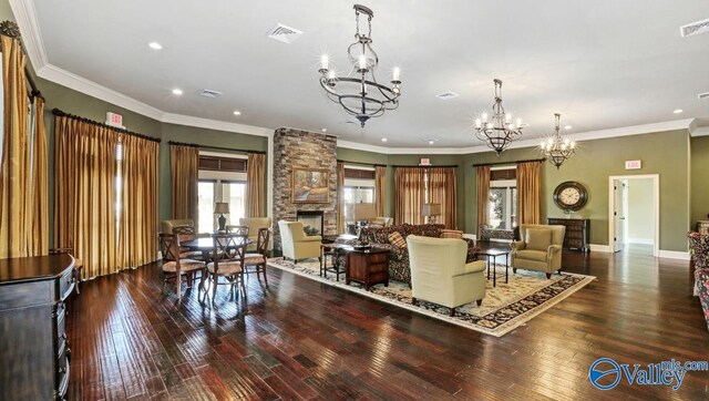 living room featuring ornamental molding, a notable chandelier, a fireplace, and wood-type flooring