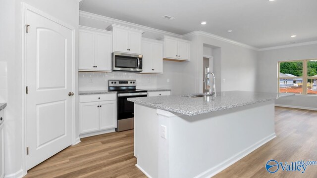 kitchen featuring appliances with stainless steel finishes, white cabinetry, a kitchen island with sink, and light wood-type flooring