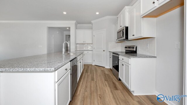 kitchen with appliances with stainless steel finishes, white cabinets, light wood-type flooring, and an island with sink