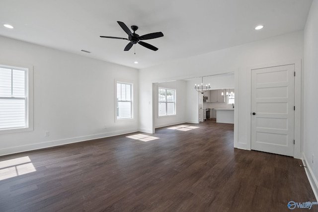 unfurnished living room with dark wood-type flooring and ceiling fan with notable chandelier