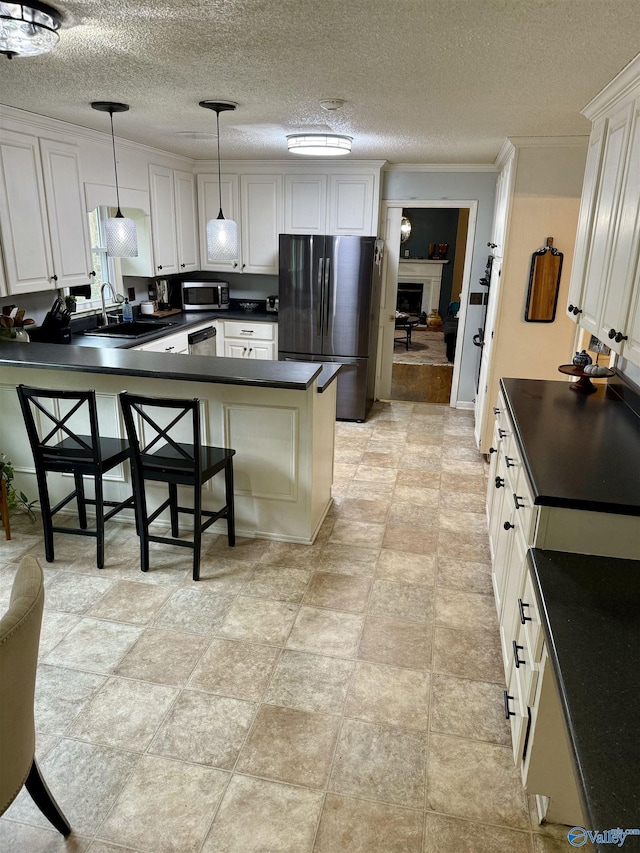 kitchen featuring kitchen peninsula, stainless steel appliances, decorative light fixtures, white cabinetry, and a breakfast bar area