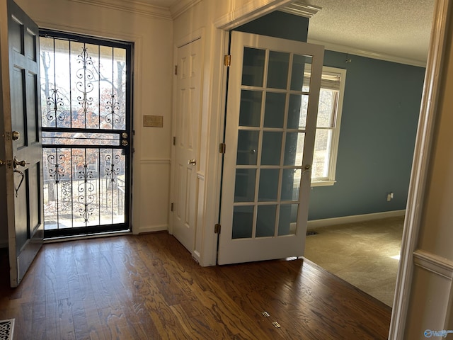 carpeted foyer entrance featuring crown molding and a textured ceiling