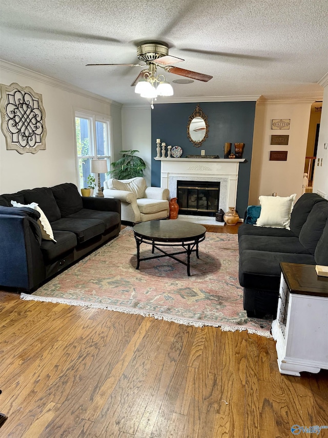 living room with a textured ceiling, hardwood / wood-style flooring, ceiling fan, and crown molding