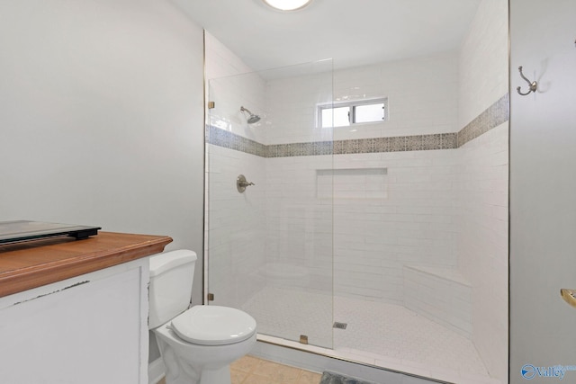 bathroom featuring toilet, tile patterned floors, and tiled shower