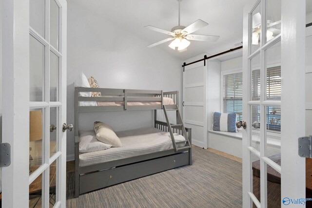 bedroom featuring ceiling fan, french doors, and a barn door