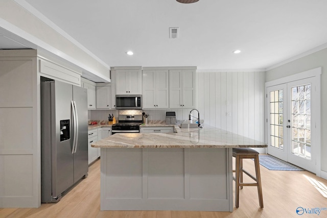 kitchen featuring appliances with stainless steel finishes, french doors, light stone countertops, crown molding, and sink