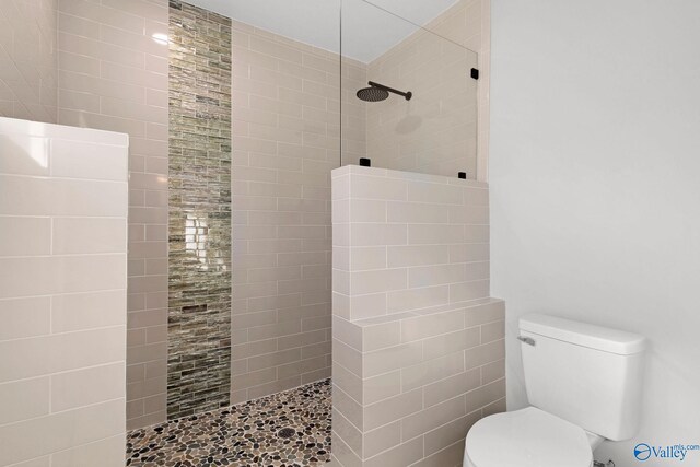 bathroom featuring toilet and a tile shower