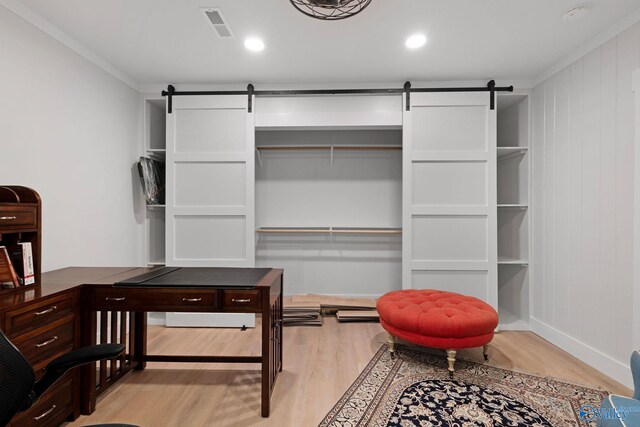 walk in closet featuring a barn door and light hardwood / wood-style floors