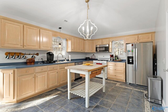 kitchen featuring a wealth of natural light, decorative light fixtures, stainless steel appliances, sink, and a chandelier