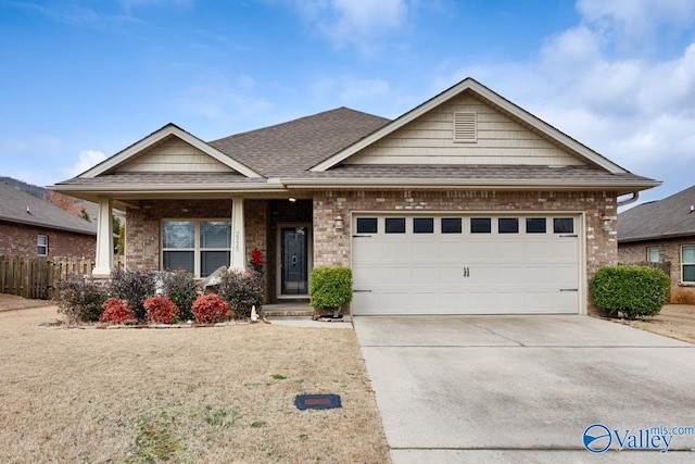 view of front of home featuring driveway, brick siding, and roof with shingles