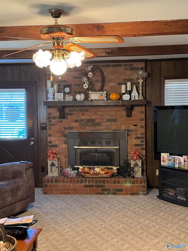 living room featuring carpet, wood walls, beamed ceiling, and a brick fireplace