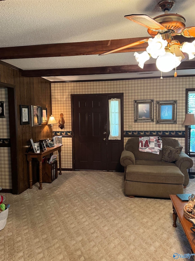 living room featuring beamed ceiling, light carpet, a textured ceiling, and wooden walls