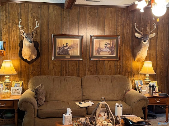 carpeted living room featuring beamed ceiling and wood walls