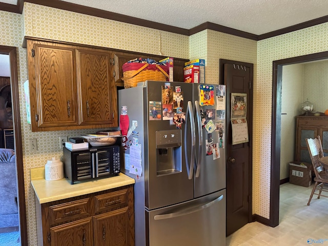 kitchen featuring stainless steel fridge, ornamental molding, and a textured ceiling