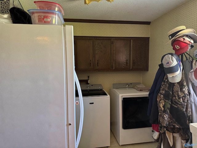 laundry area with cabinets, crown molding, washing machine and dryer, a textured ceiling, and light tile patterned flooring