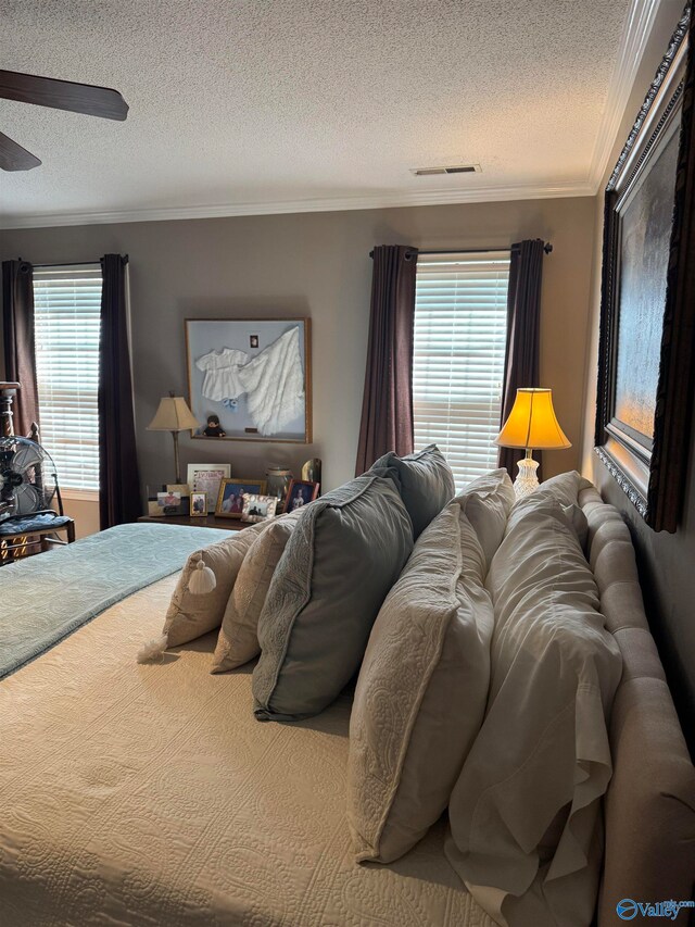 bedroom featuring a textured ceiling, ceiling fan, and ornamental molding