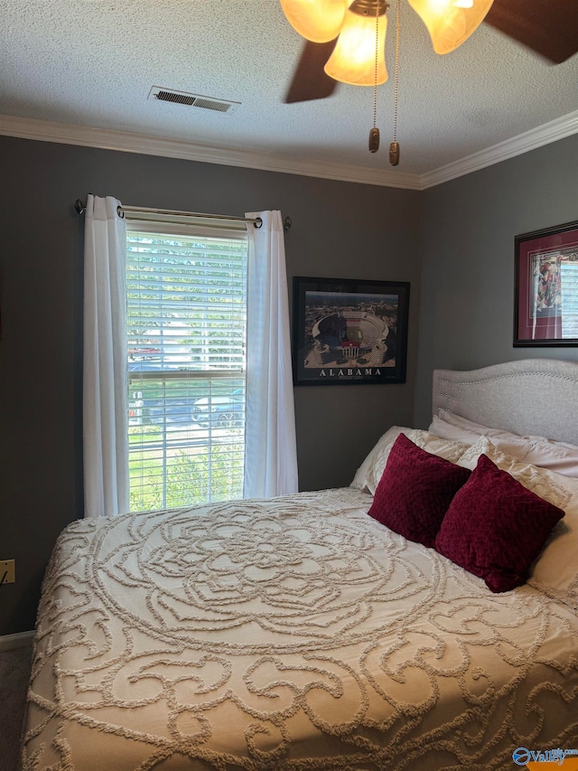 bedroom featuring ceiling fan, crown molding, and a textured ceiling