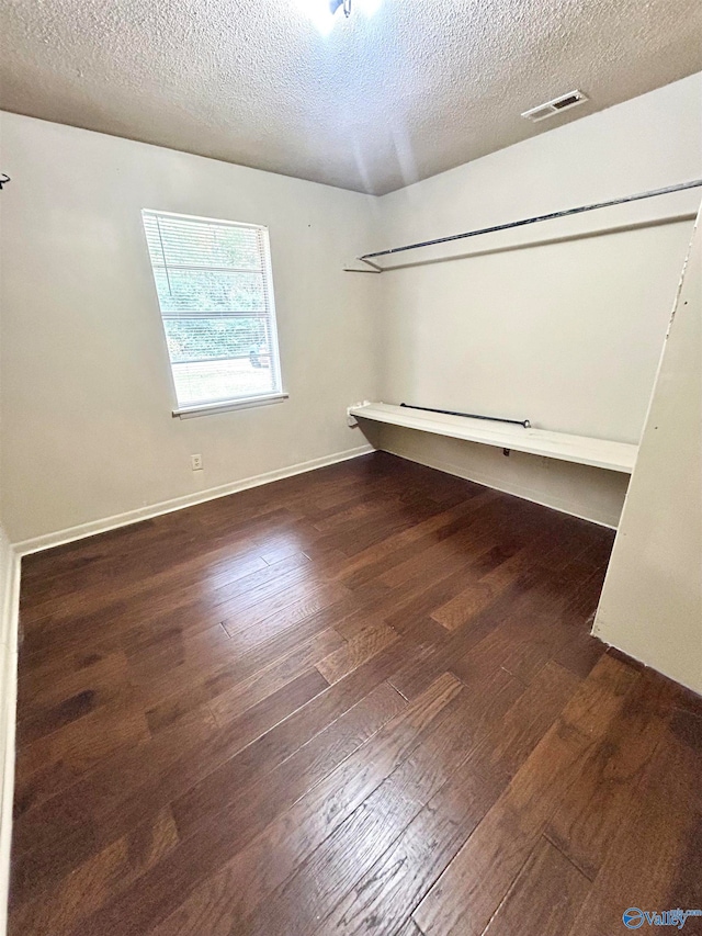 unfurnished room with dark wood-type flooring and a textured ceiling