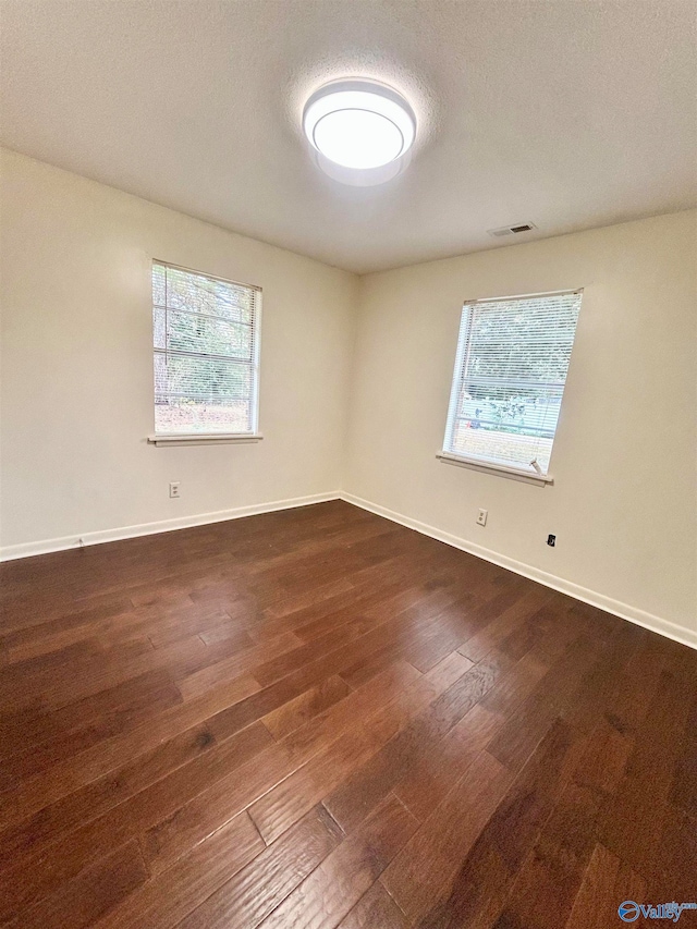 unfurnished room featuring dark wood-type flooring and a textured ceiling