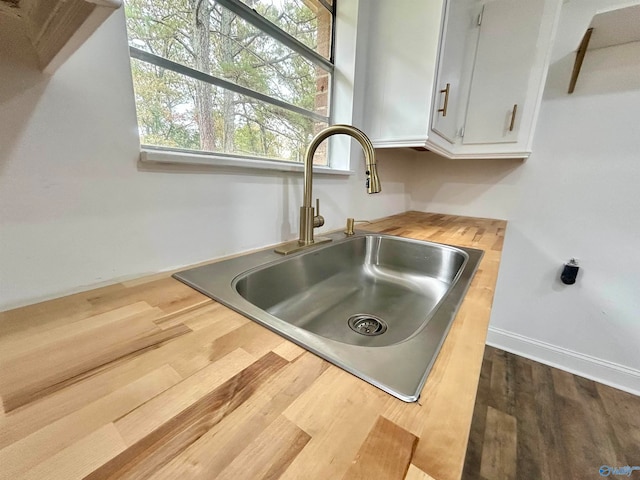 interior details featuring white cabinets, hardwood / wood-style flooring, and sink