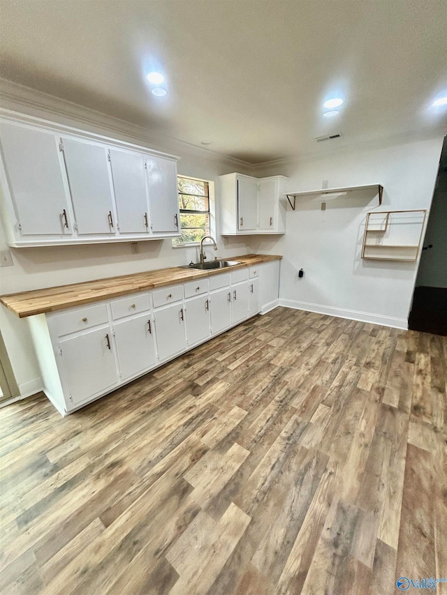 kitchen featuring light hardwood / wood-style floors, sink, wooden counters, and white cabinets