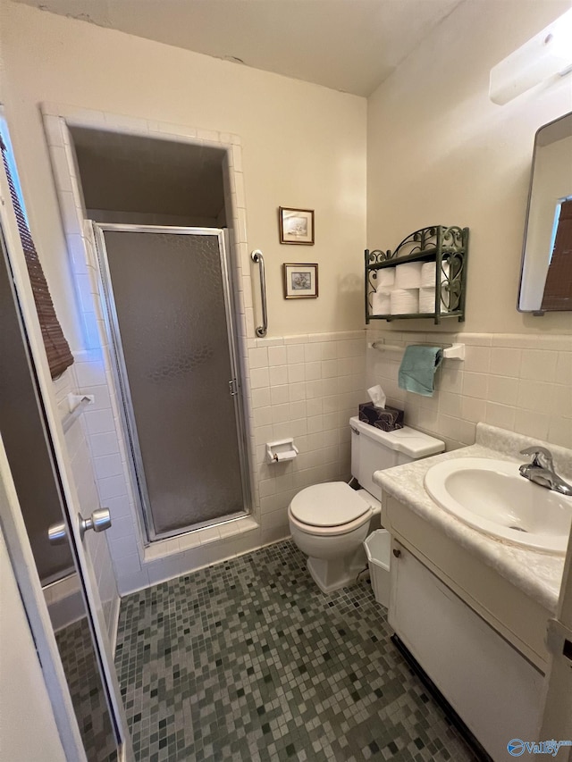 bathroom featuring tile patterned flooring, vanity, tile walls, toilet, and walk in shower