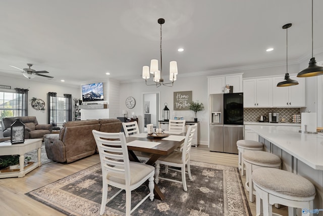 dining room with ceiling fan with notable chandelier, light hardwood / wood-style floors, and crown molding