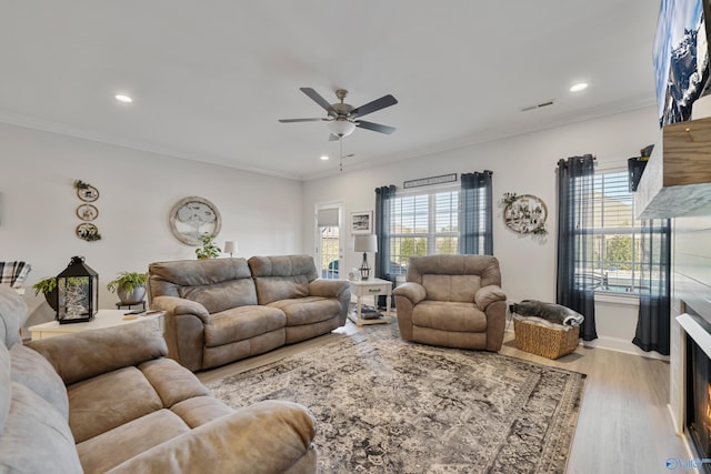 living room with ceiling fan, light hardwood / wood-style floors, crown molding, and a wealth of natural light